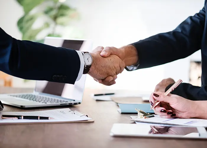 Two businesspeople shaking hands across a desk