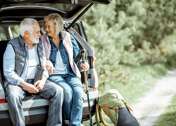 Retirement age couple sitting in back of SUV after taking a hike