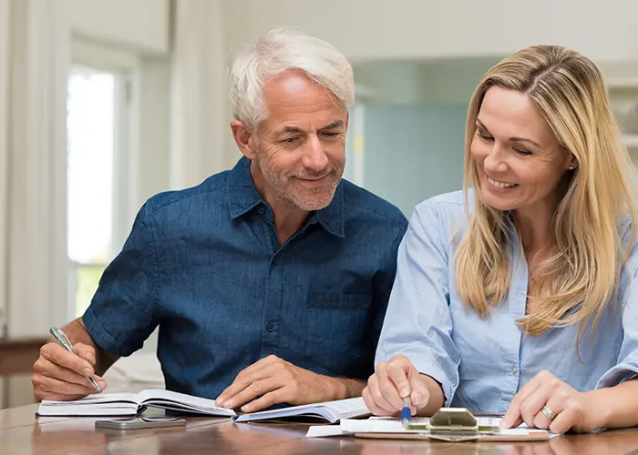 Older couple with clipboard and notebook reviewing retirement income