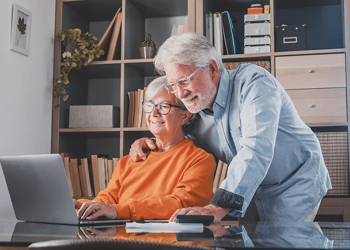 Retirement age couple at desk looking at annuities on laptop